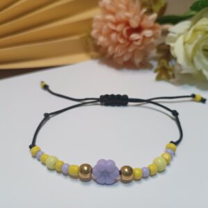 Pulseira com contas de vidro amarela e lilases, entremeios em lilás e contas metálicas em ouro velho, fios pretos e fecho em macramê ajustável