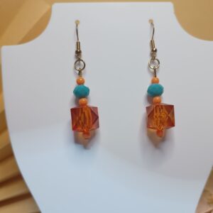 Brincos com cristais turquesa, pingentes na forma de cubo na cor coral translúcidos e contas plásticas na cor coral, com base anzol dourada