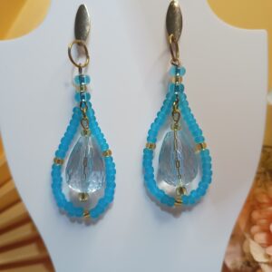 Brincos grandes com miçangas na cor azul fosco, miçangas douradas, pingentes em forma de gota na cor azul translúcido e argolas e base ovais dourados