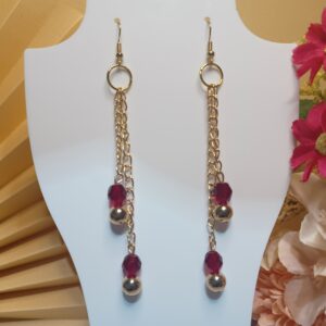 Brincos longos com argolas, correntes e contas metálicas em dourado e cristais vermelho, com base anzol dourada