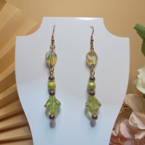 Brincos longos com contas na cor verde sextavadas, murano transparente rajado de verde e amarelo, peças na forma de losango na cor verde e peças metálicas na cor ouro velho, com base anzol