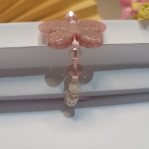 Pulseira com fio de seda rosa com cristais rosa claro translúcido e cristais na cor creme, miçangas na cor rosa claro e entremeio de borboleta resinado na cor rosa com fecho em macramê ajustável