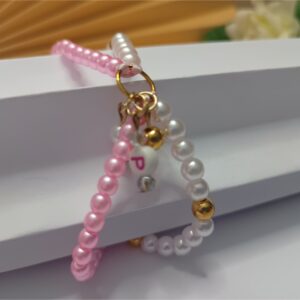 Pulseira dupla com entremeio argola e letra personalizável, contas metálicas douradas, pequenos cristais, pérolas na cora branca e rosa com fecho em macramê ajustável