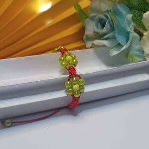 Pulseira trabalhada em macramê com fio de seda vermelho, 3 flores em pérolas na cor verde oliva com fecho ajustável