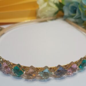 Tiara folheada a ouro 18k com aplicação de cristais na forma de losango nas cores pêssego, azul, roxo, rosa e verde translúcidos