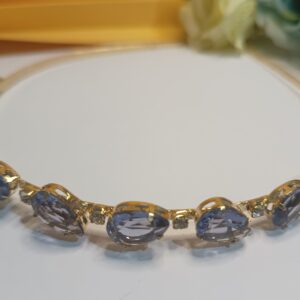 Tiara folheada a ouro 18k com cristais na forma de gota na cor roxa translúcido e aplicações de strass