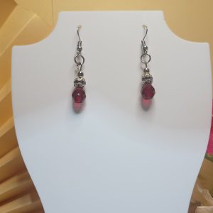 Brincos com base anzol e detalhes na cor prateada, cristais vermelhos e conta prateada trabalhada com cristais lilases